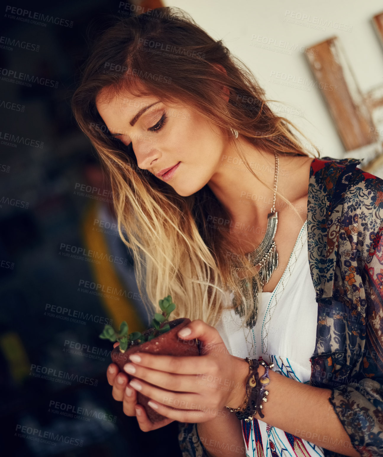 Buy stock photo Shot of a free spirited young woman admiring a pot plant in her hands