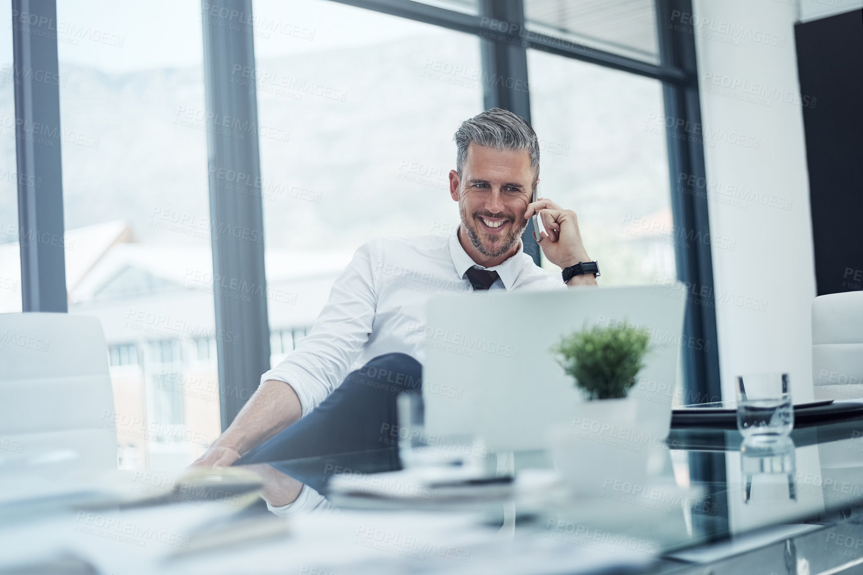 Buy stock photo Shot of a corporate businessman talking on a cellphone while working in an office