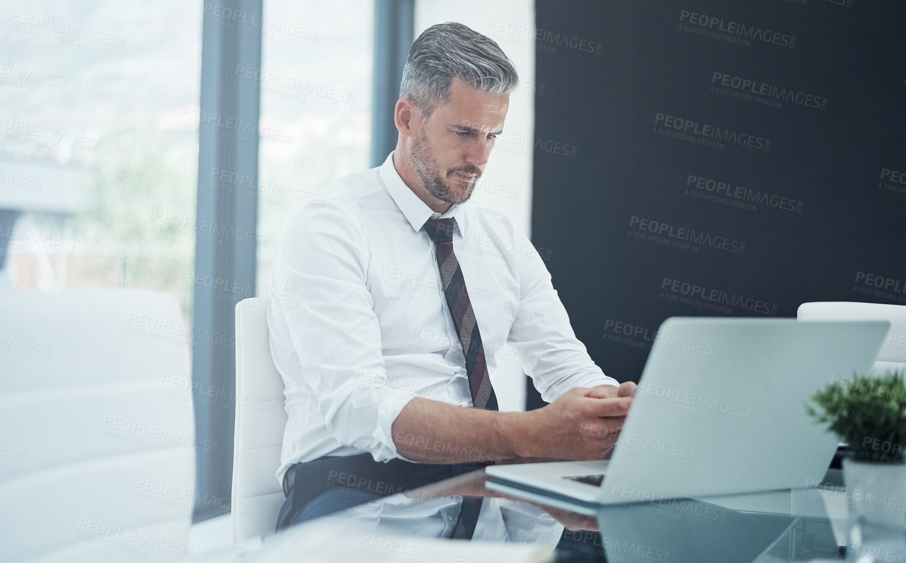 Buy stock photo Shot of a corporate businessman texting on a cellphone while working in an office