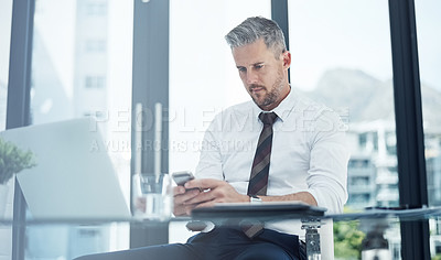 Buy stock photo Shot of a corporate businessman texting on a cellphone while working in an office