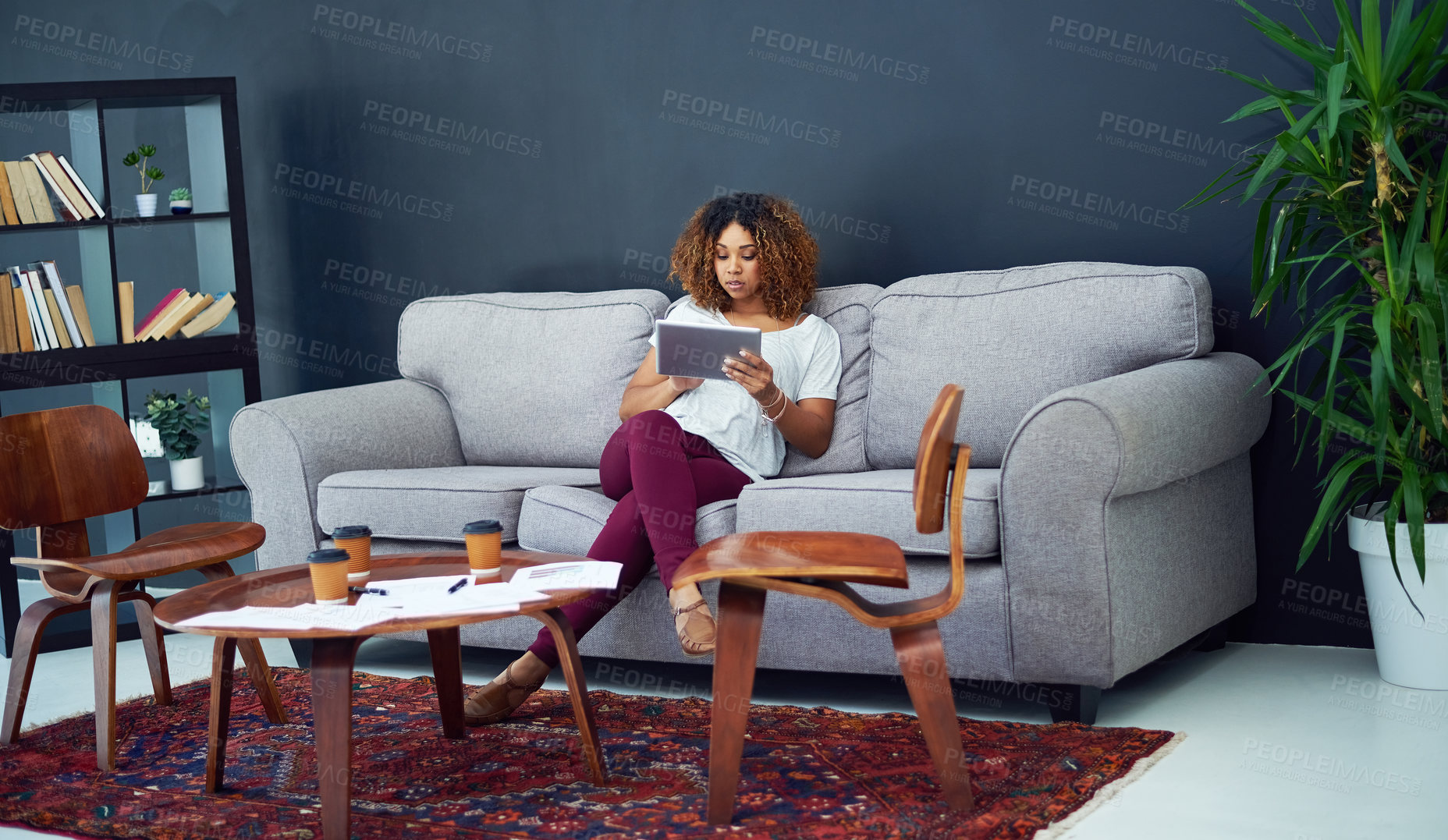 Buy stock photo Shot of a young businesswoman using a digital tablet on the sofa in a modern office