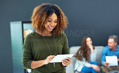 Buy stock photo Shot of a young businesswoman using a digital tablet with her team in the background