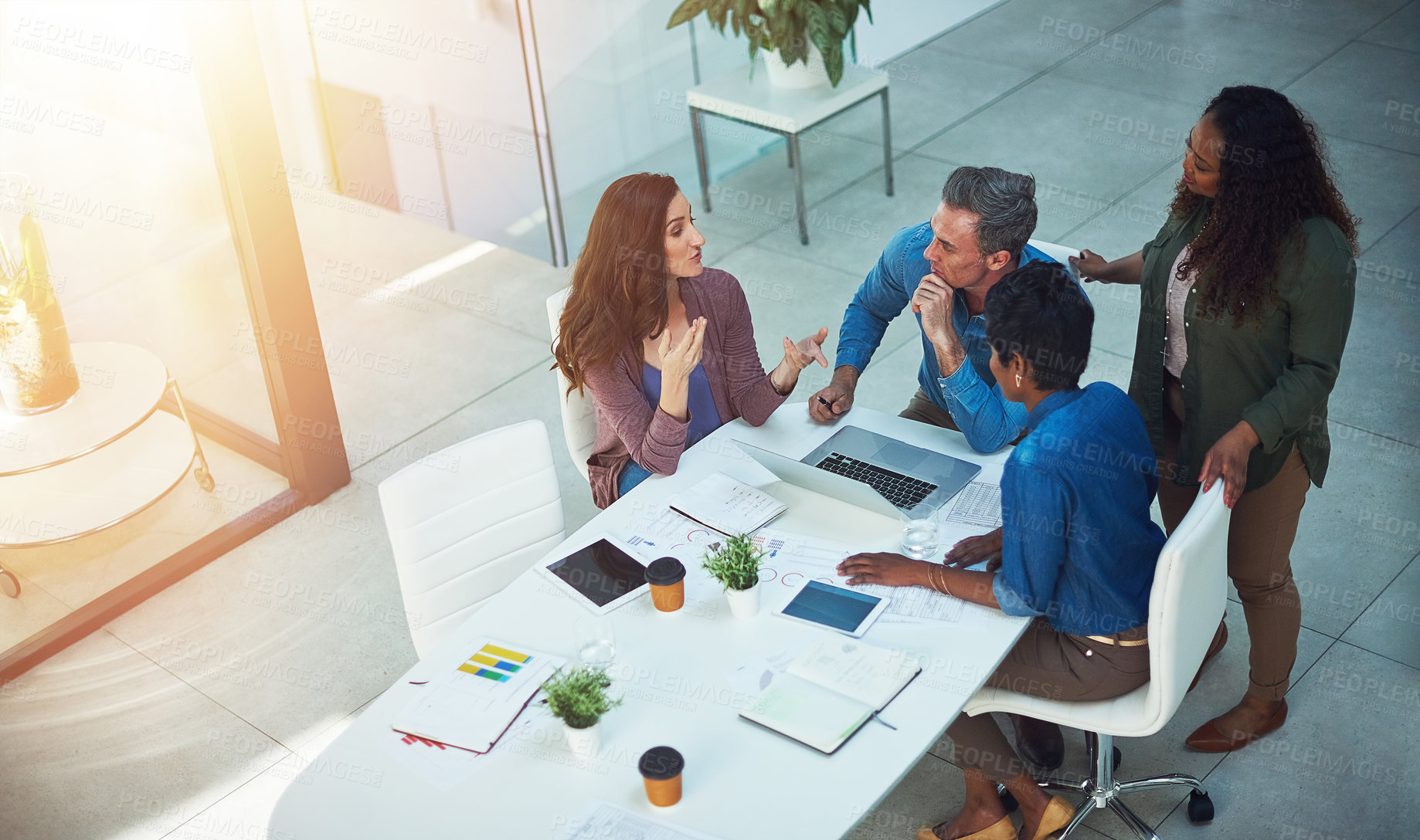 Buy stock photo Shot of a group of designers gathering around a man using a laptop in a meeting