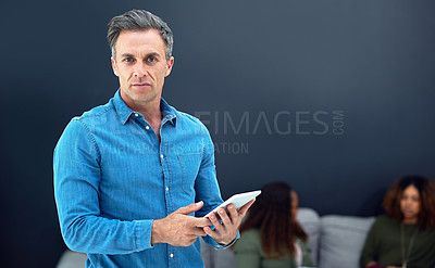 Buy stock photo Portrait of a mature businessman using a digital tablet with his team in the background