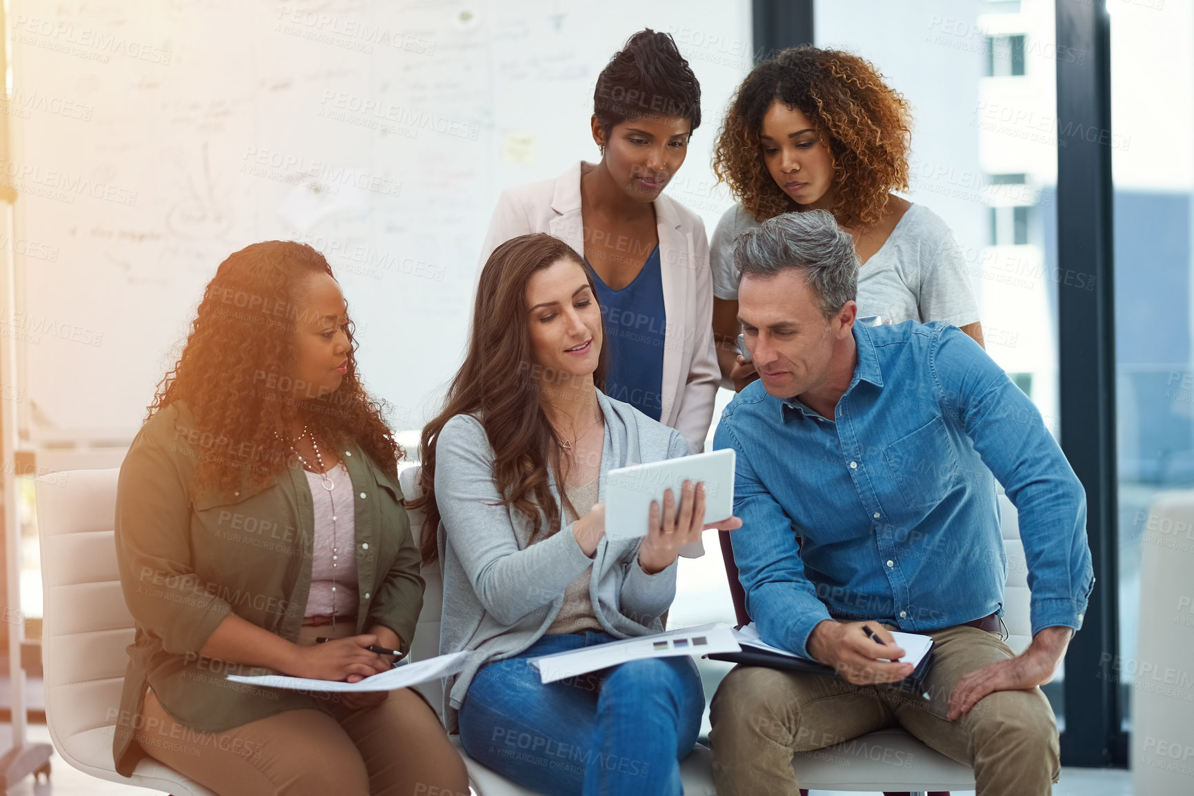 Buy stock photo Shot of a creative team using a digital tablet together during a meeting at work