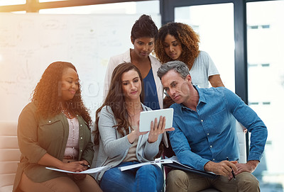 Buy stock photo Shot of a creative team using a digital tablet together during a meeting at work