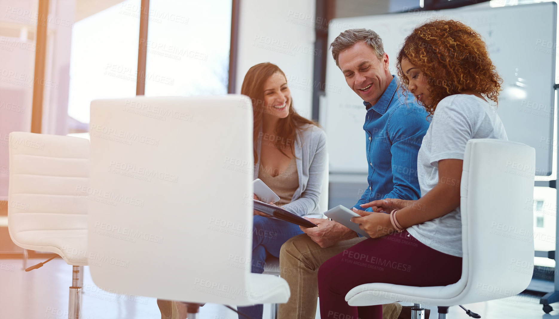 Buy stock photo Shot of a creative team using a digital tablet together during a meeting at work