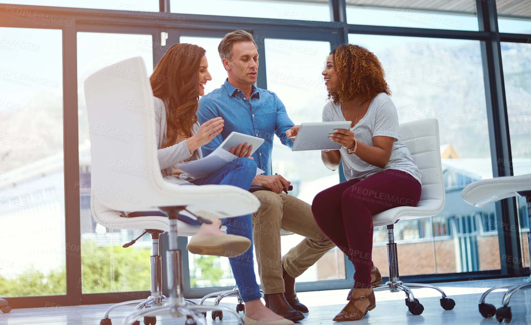 Buy stock photo Shot of a creative team using a digital tablet together during a meeting at work