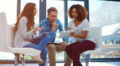 Buy stock photo Shot of a creative team using a digital tablet together during a meeting at work