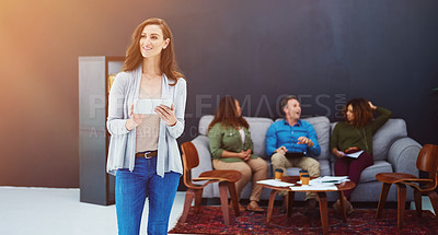 Buy stock photo Shot of a young businesswoman using a digital tablet with her team in the background