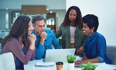 Buy stock photo Shot of a group of designers gathering around a man using a laptop in a meeting