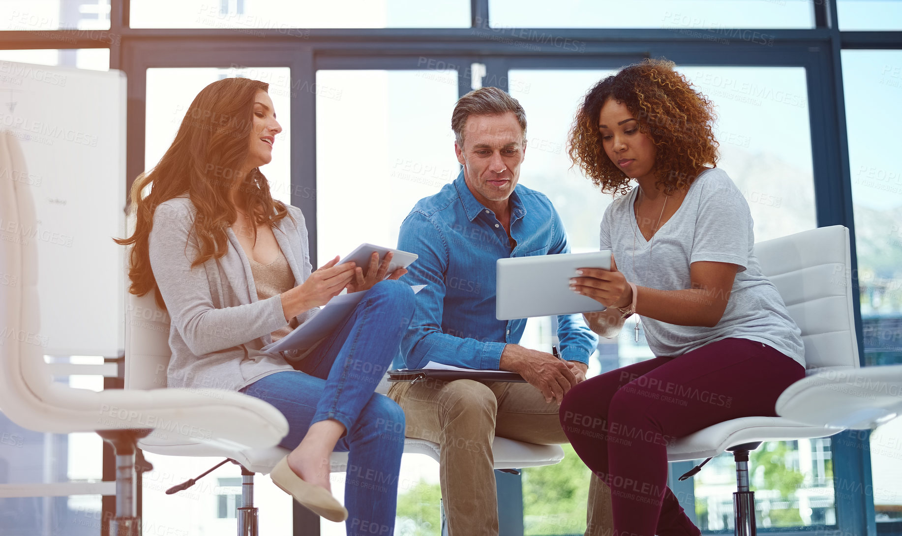 Buy stock photo Shot of a creative team using a digital tablet together during a meeting at work