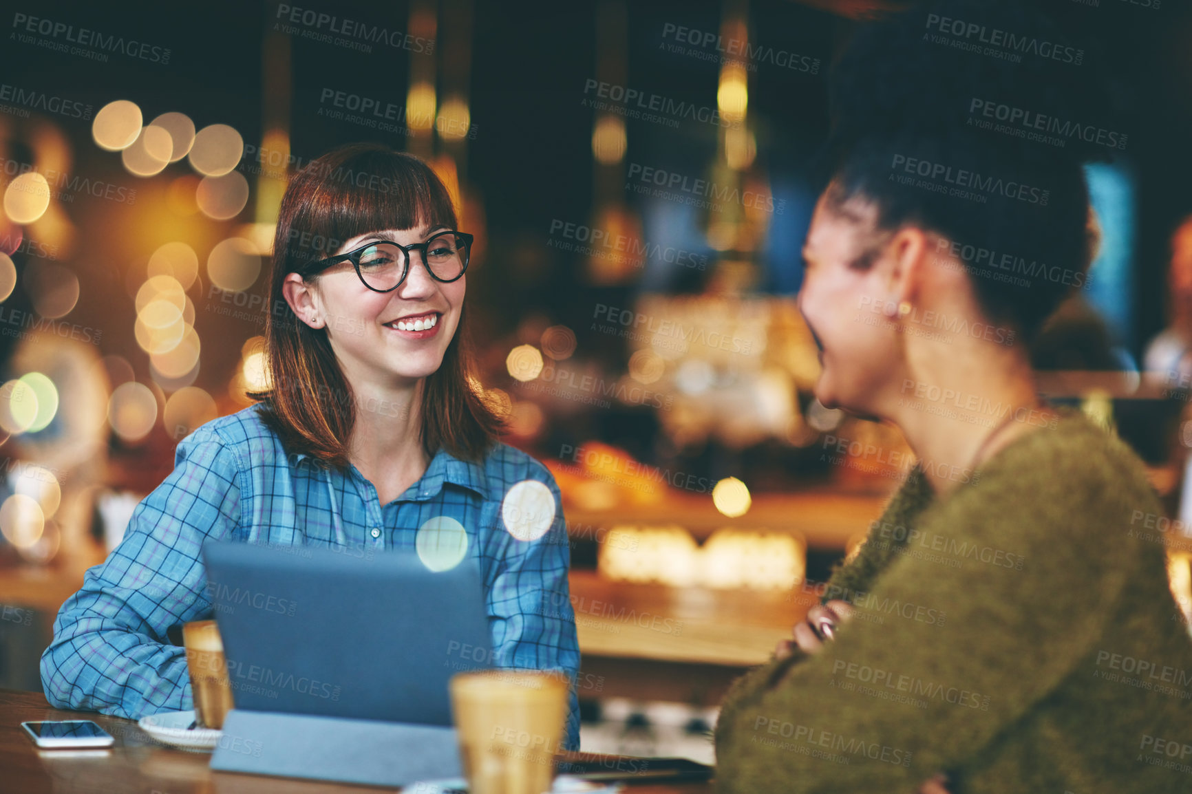 Buy stock photo Shot of two young friends hanging out together in a cafe