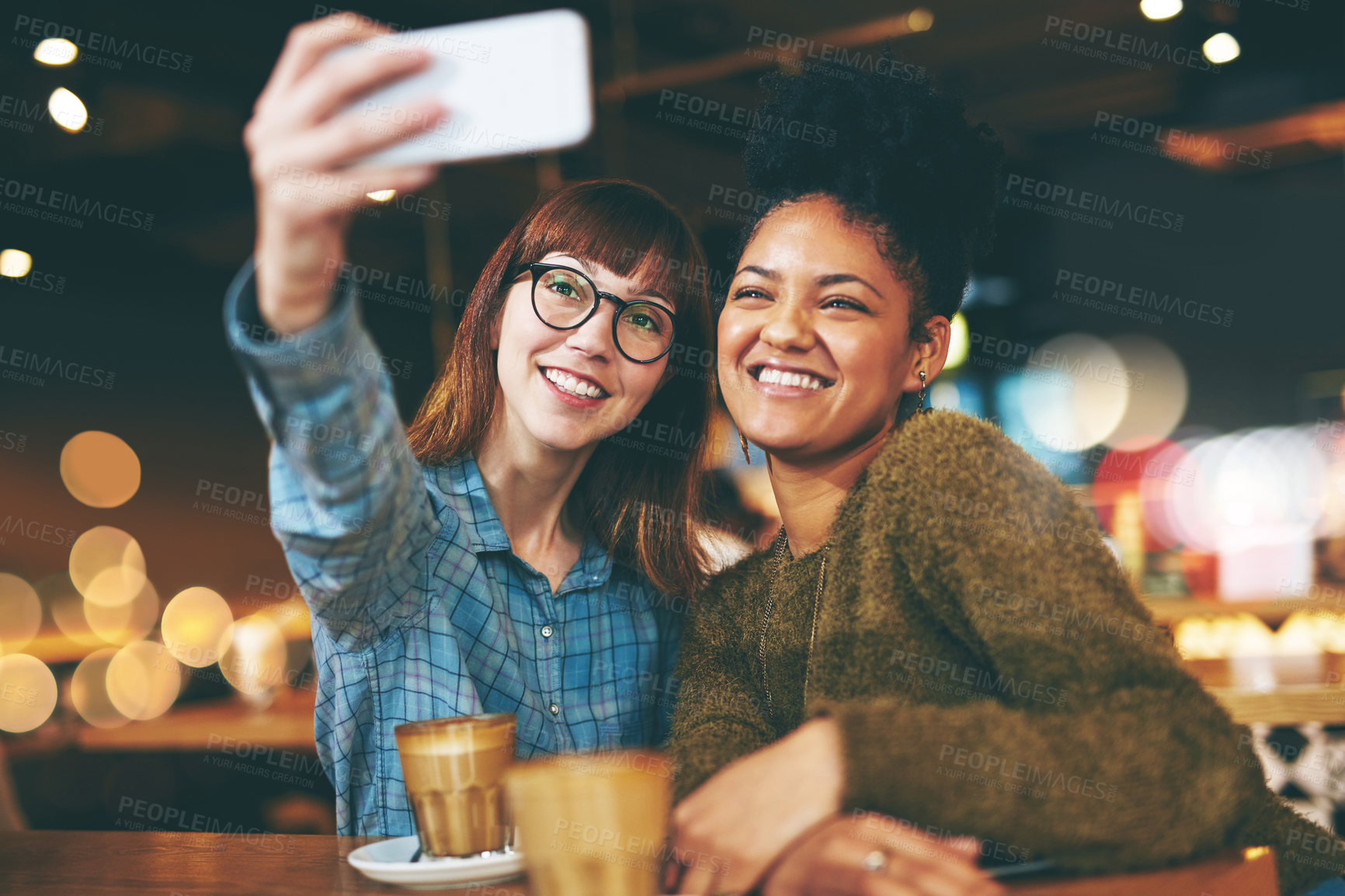 Buy stock photo Shot of two young friends taking a selfie together in a cafe