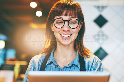 Buy stock photo Shot of a young business owner using a digital tablet in her cafe