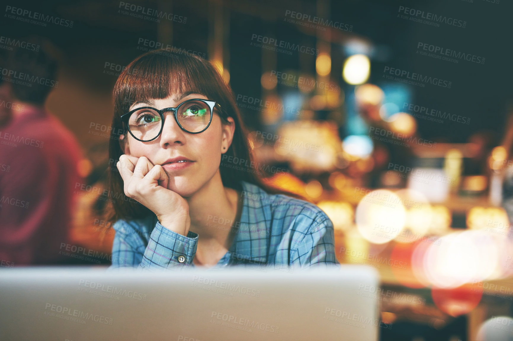 Buy stock photo Shot of an attractive young woman looking thoughtful while using her laptop in a cafe