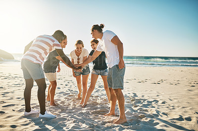 Buy stock photo Shot of a group of young joining their hands together in solidarity at the beach