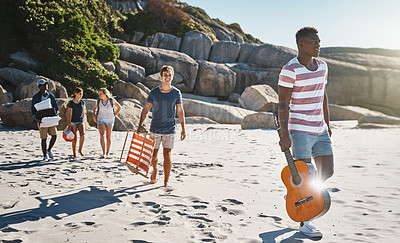 Buy stock photo Shot of a group of young friends walking on the beach on a sunny day