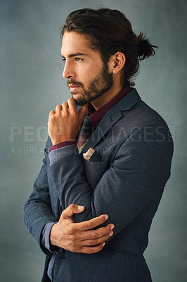 Buy stock photo Studio shot of a stylishly dressed handsome young man standing with his hand on his chin