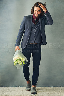 Buy stock photo Studio shot of a stylishly dressed handsome young man smiling and holding a bouquet of flowers