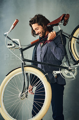 Buy stock photo Studio shot of a stylishly dressed handsome young man carrying his bicycle