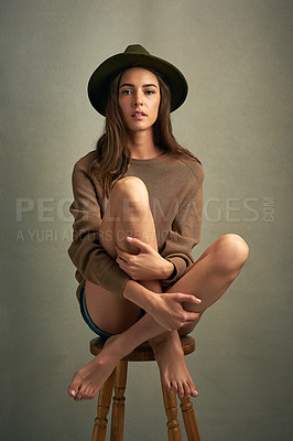 Buy stock photo Shot of a beautiful young woman sitting against a brown background