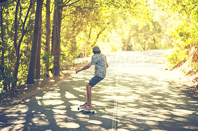 Buy stock photo Rearview shot of a young man longboarding in the street