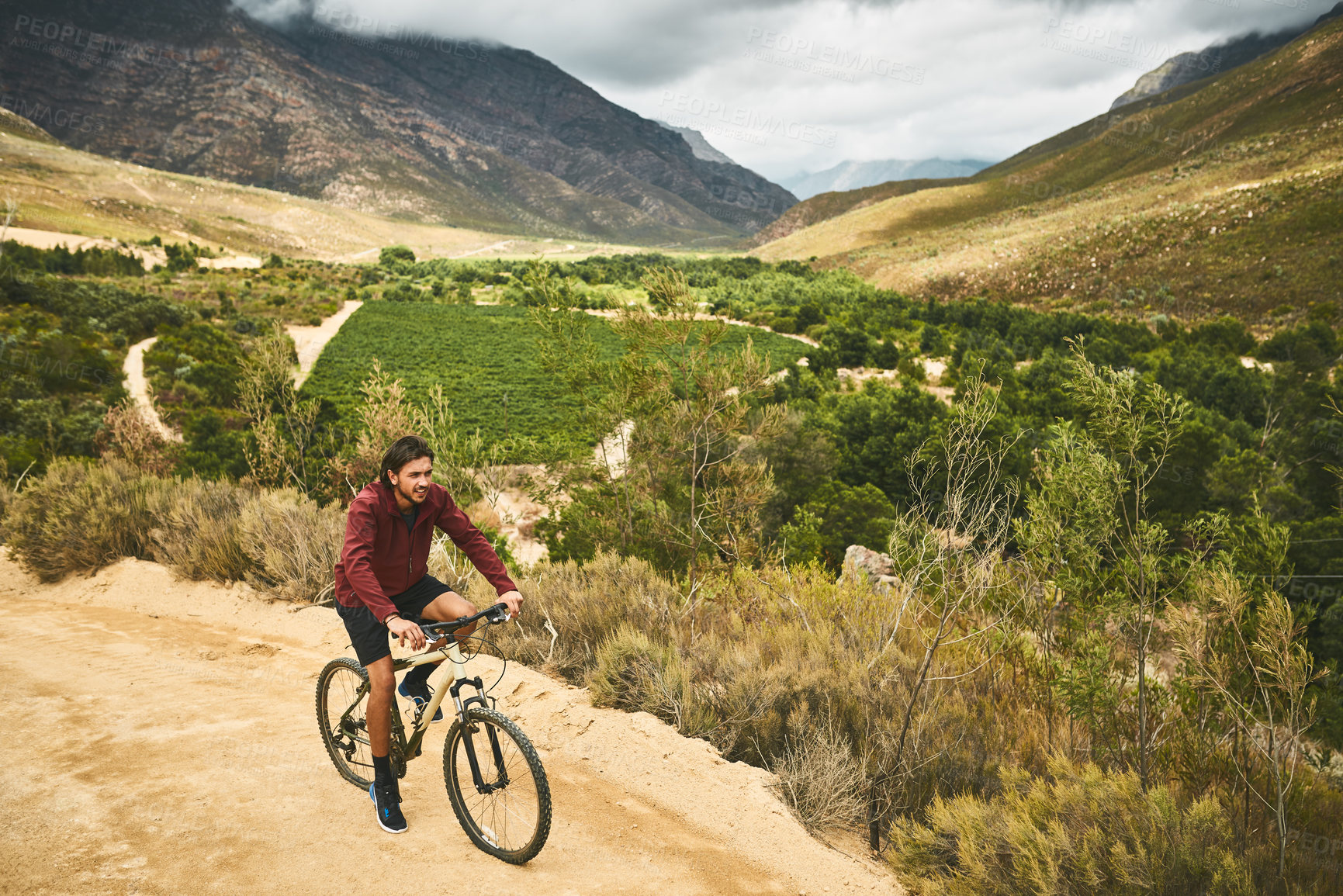 Buy stock photo Shot of a young man cycling along a trail