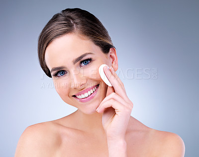 Buy stock photo Studio portrait of an attractive young woman using a cotton pad on her face against a gray background