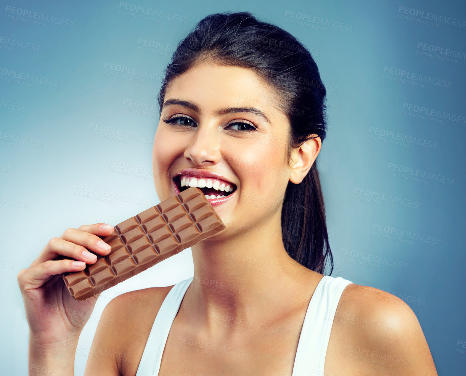 Buy stock photo Woman, portrait and happy, snack and chocolate for treat or delicious while isolated on blue background. Smile, enjoyment and face, beauty with female model in studio and tasting dessert for pleasure