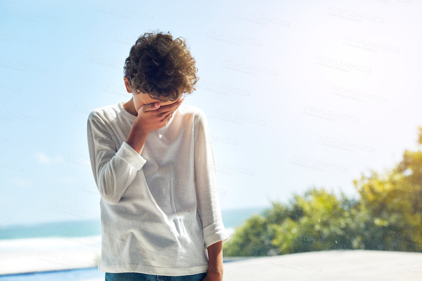 Buy stock photo Cropped shot of a little boy covering his face in sadness