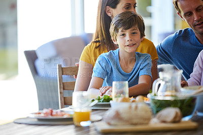 Buy stock photo Portrait of a little boy enjoying a meal with his family at home