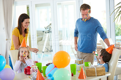 Buy stock photo Shot of a happy family playing with party horns at a birthday party