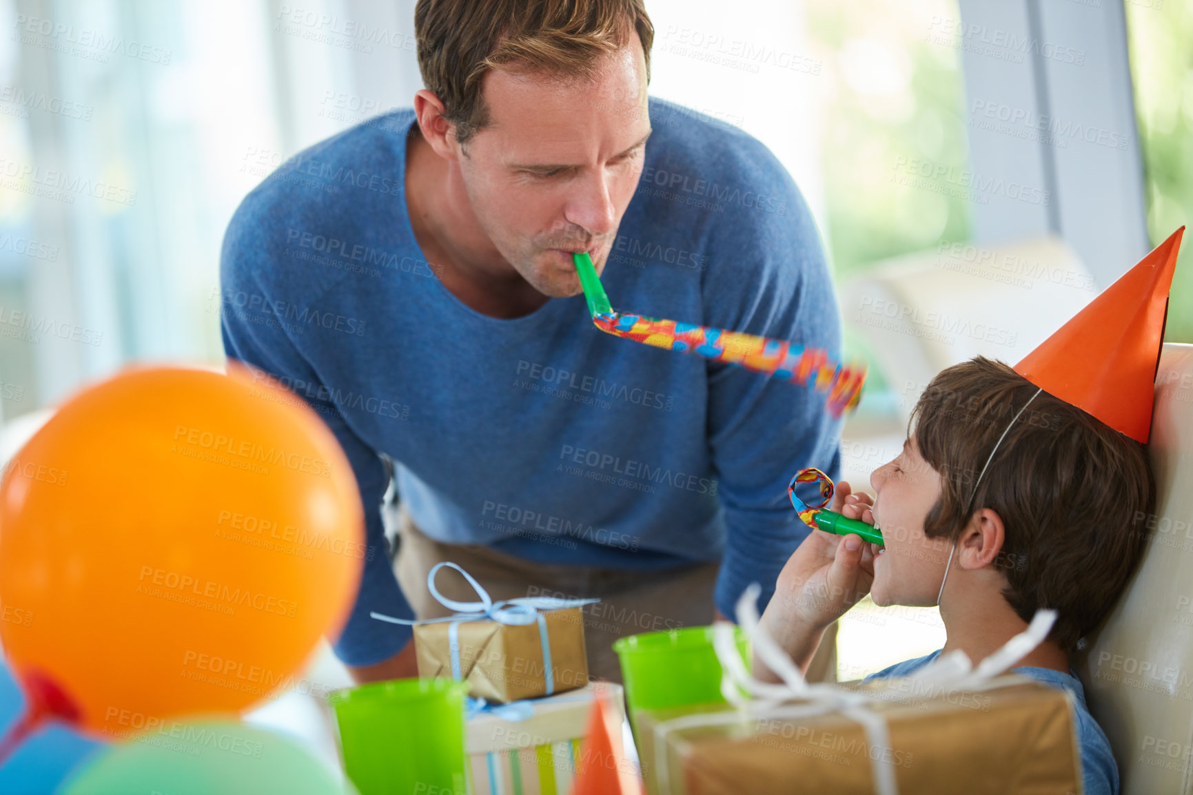 Buy stock photo Shot of a father and son playing with party horns at a birthday party