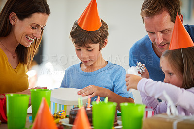 Buy stock photo Shot of a little boy opening his birthday presents surrounded by his family
