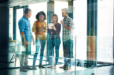 Buy stock photo Full length shot of four young coworkers talking while looking at a digital tablet
