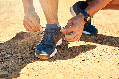 Buy stock photo Cropped shot of an unidentifiable man tying his shoelaces outside