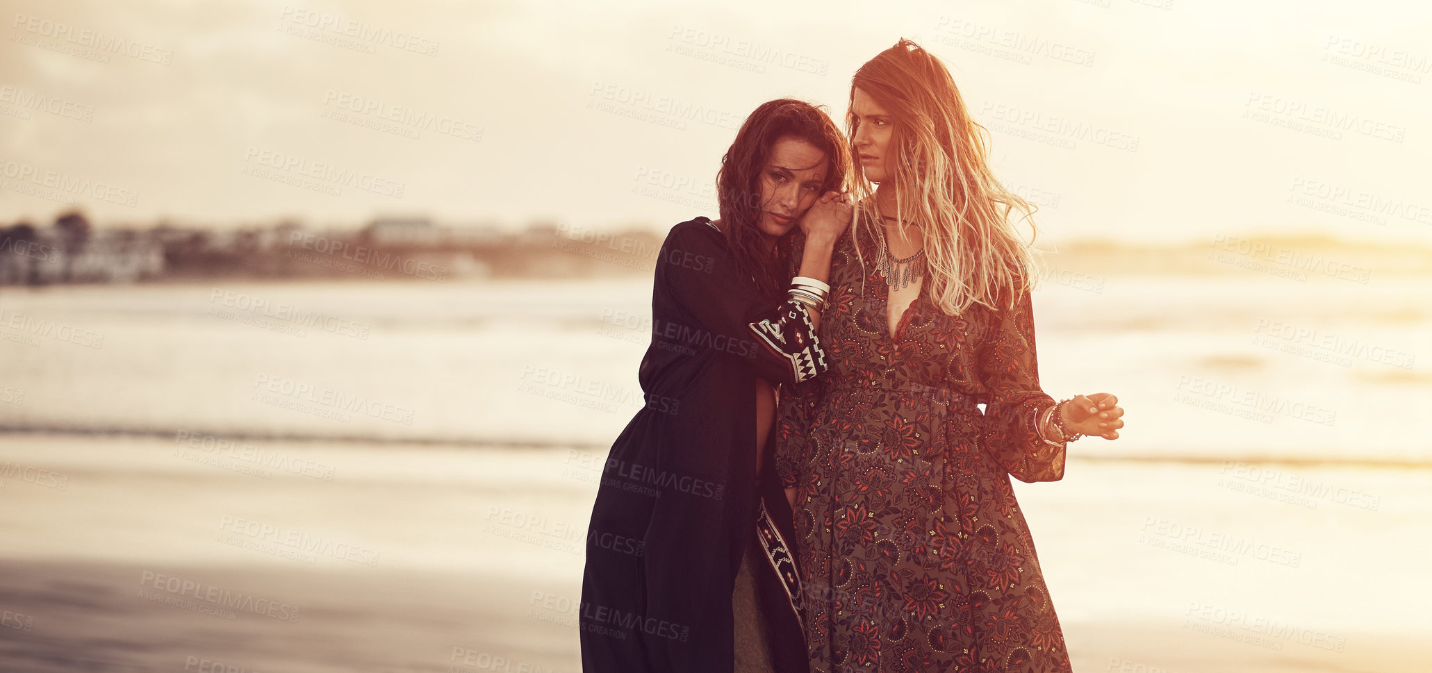 Buy stock photo Shot of two young women spending the day at the beach at sunset