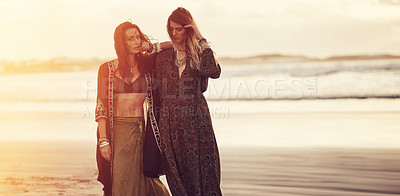 Buy stock photo Shot of two young women spending the day at the beach at sunset