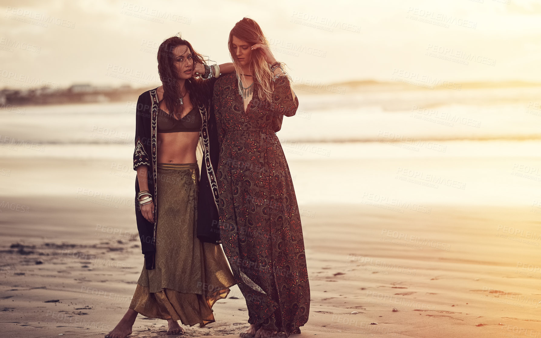 Buy stock photo Shot of two young women spending the day at the beach at sunset