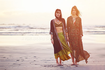 Buy stock photo Shot of two young women spending the day at the beach at sunset