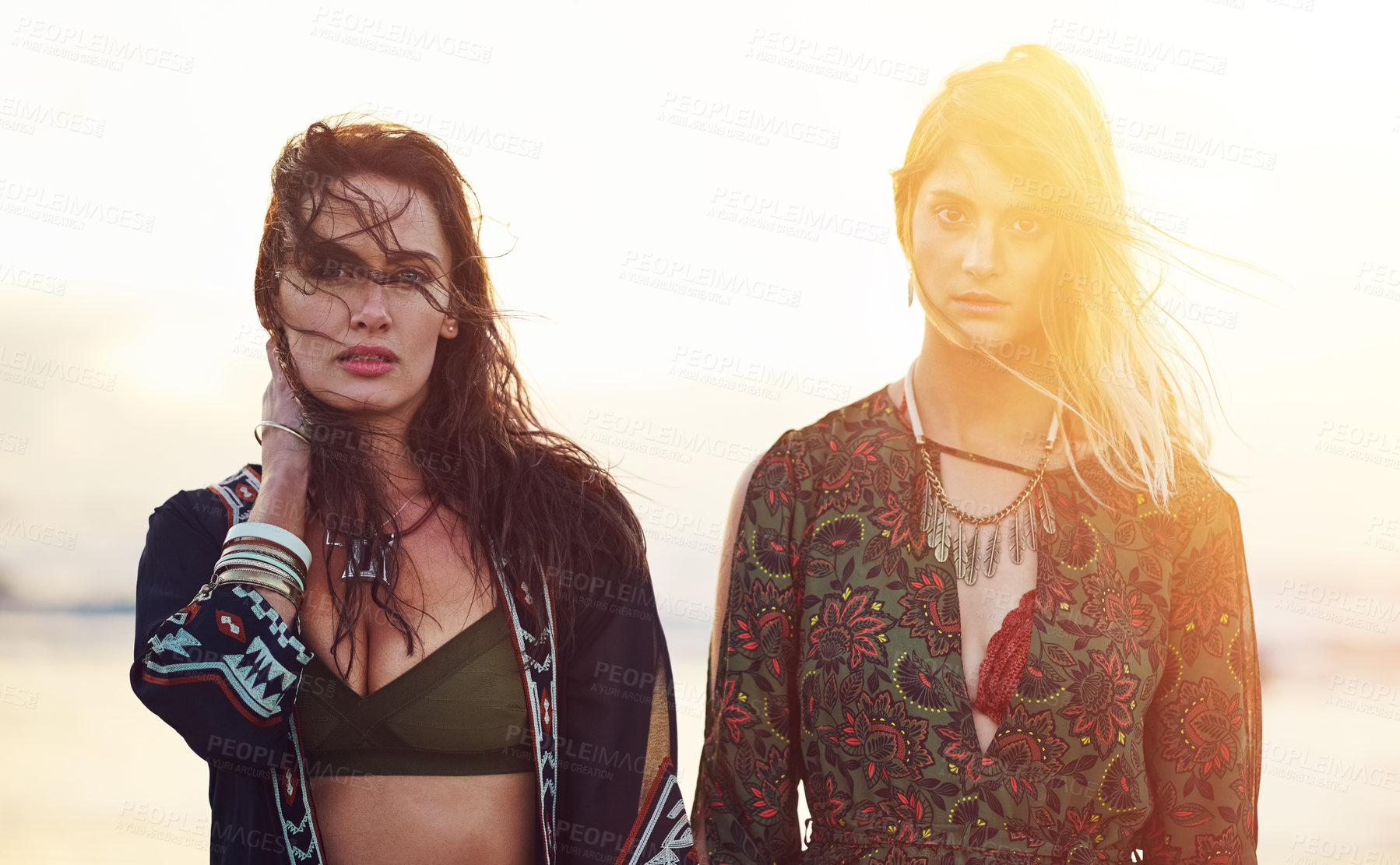 Buy stock photo Shot of two young women spending the day at the beach at sunset