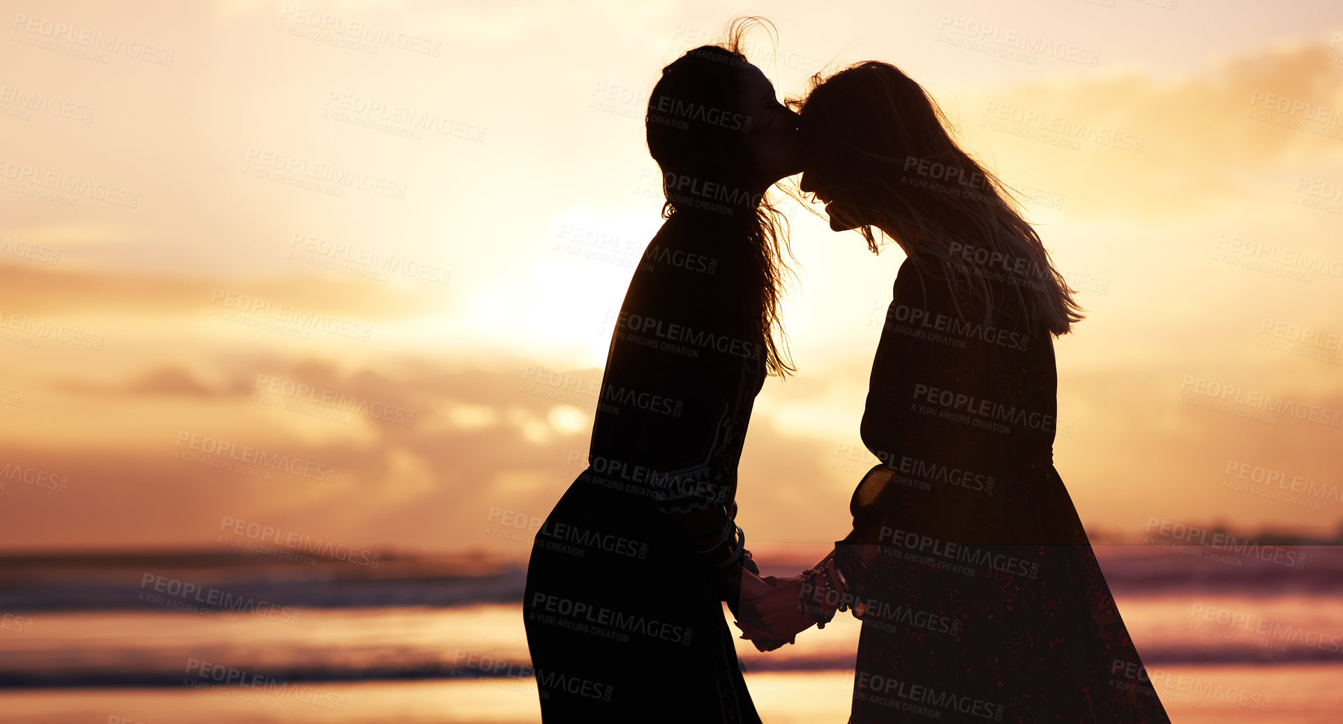 Buy stock photo Shot of two young women spending the day at the beach at sunset