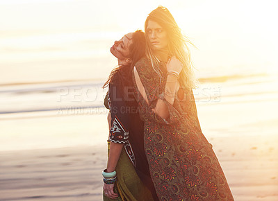 Buy stock photo Shot of two young women spending the day at the beach at sunset