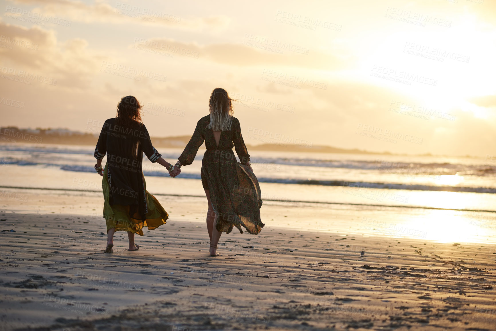 Buy stock photo Shot of two young women spending the day at the beach at sunset