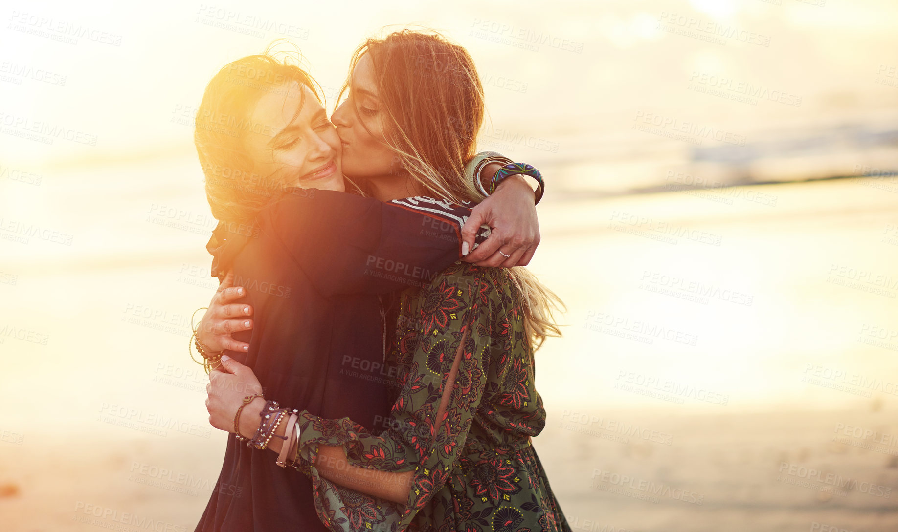 Buy stock photo Shot of two young women spending the day at the beach at sunset