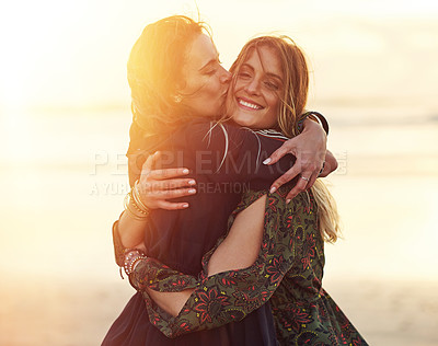 Buy stock photo Shot of two young women spending the day at the beach at sunset