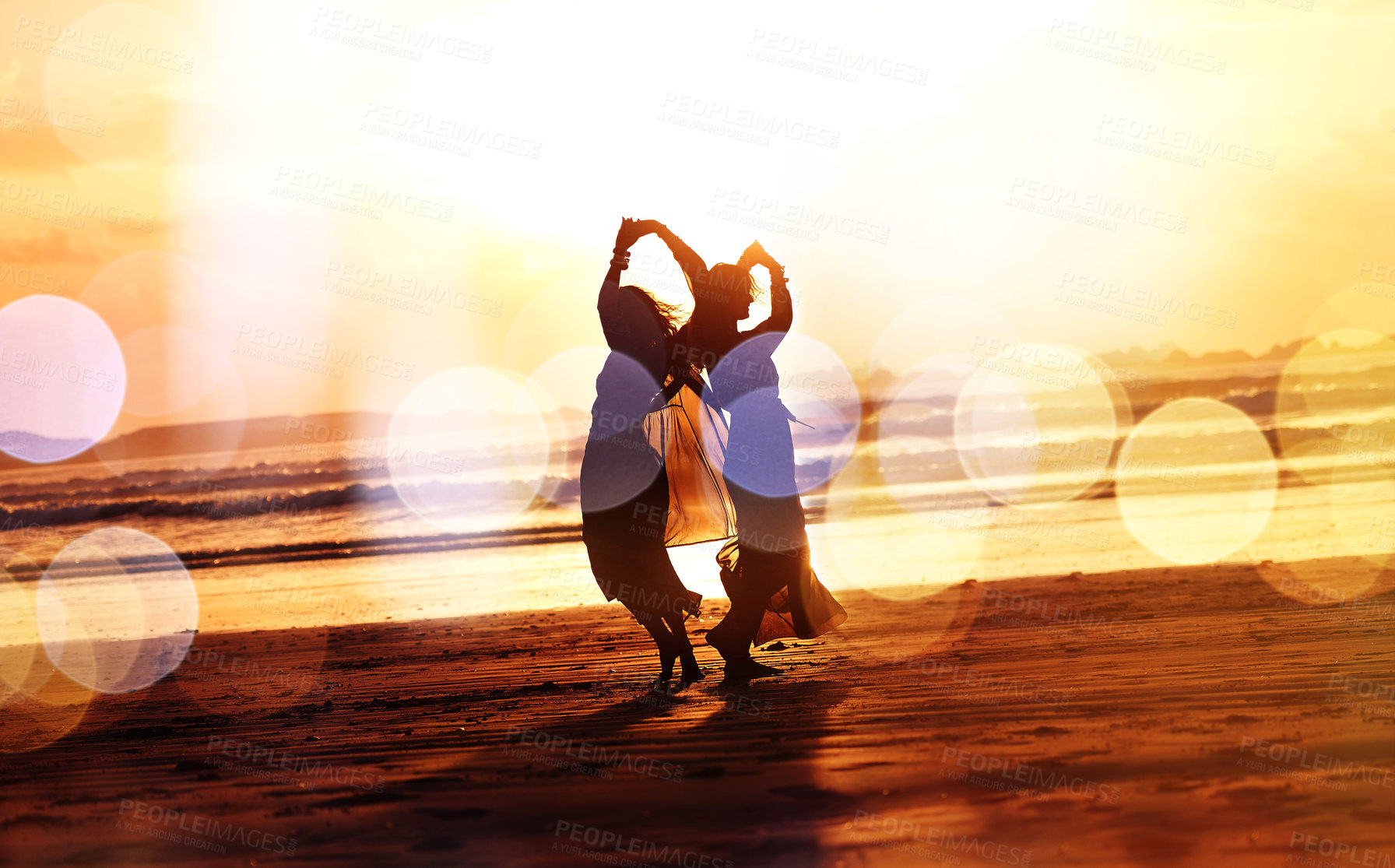 Buy stock photo Shot of two young women spending the day at the beach at sunset