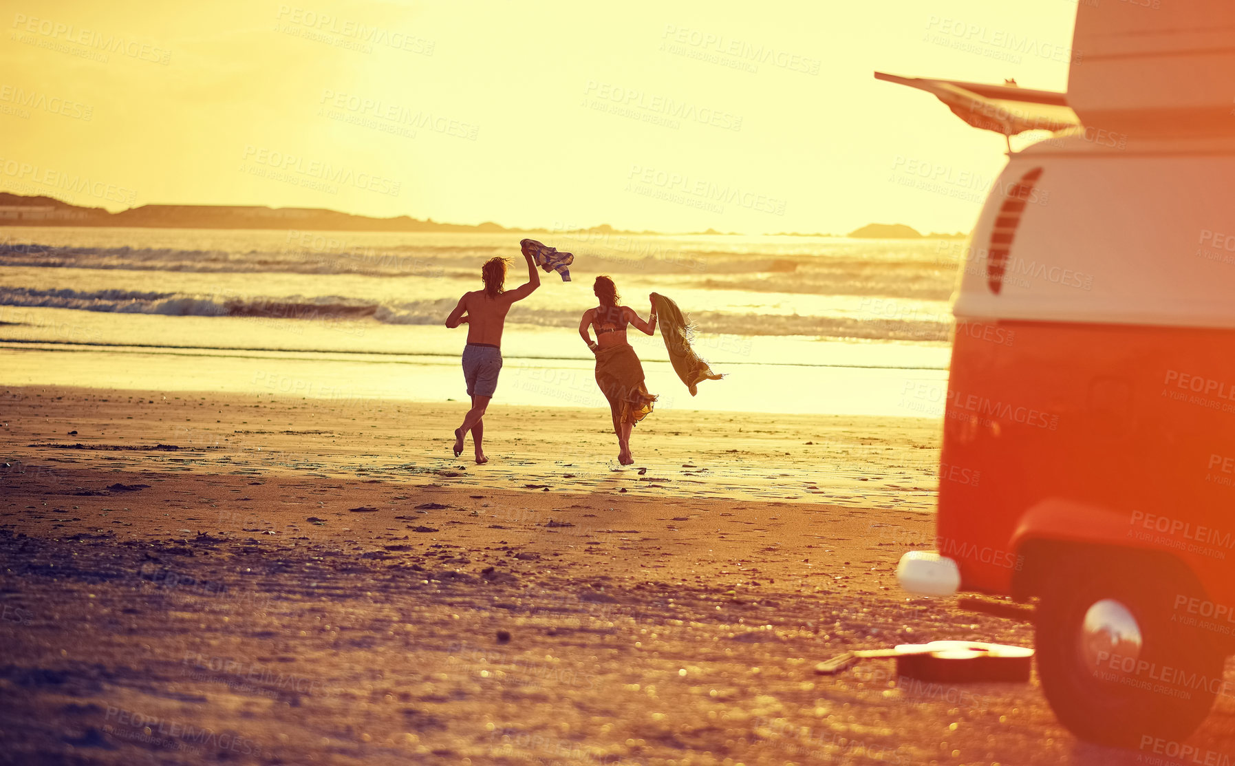 Buy stock photo Rearview shot of a young couple running towards the water on a beach