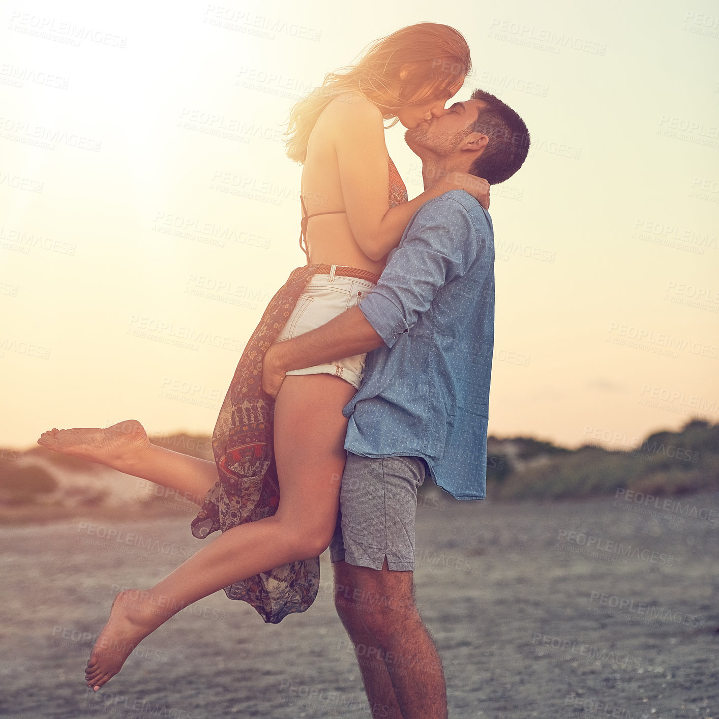 Buy stock photo Shot of an affectionate young couple at the beach